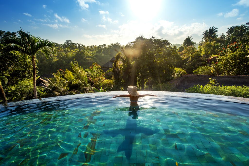 Luxury solo female travel at its best - woman luxuriates at the edge of an infinity pool