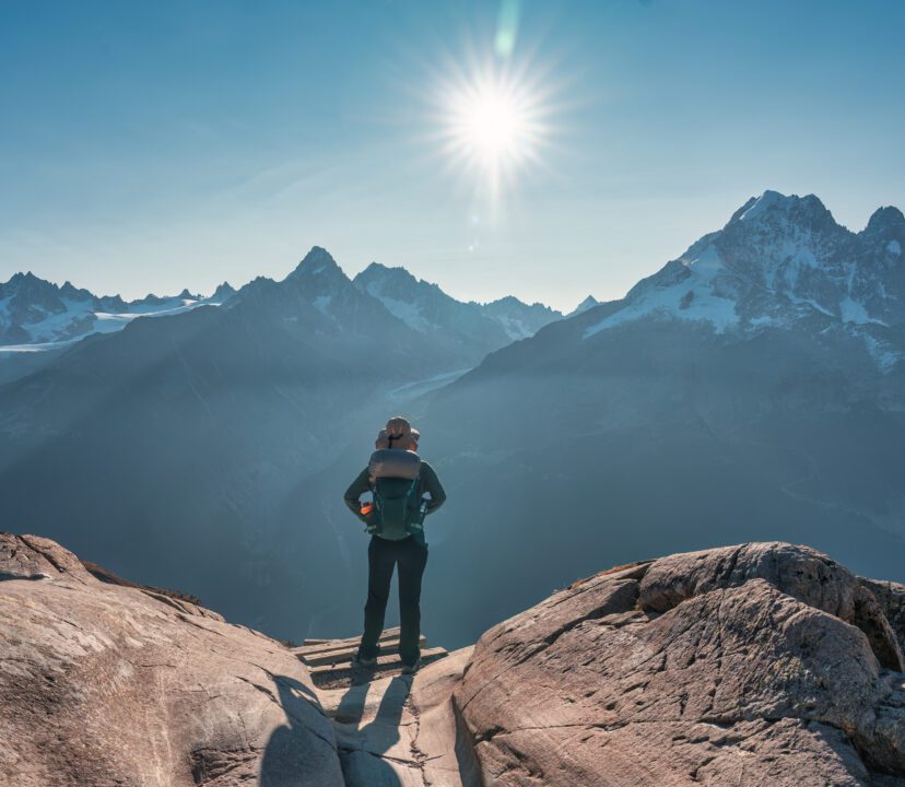 Female explorer stood atop a mountain looking across the valley.