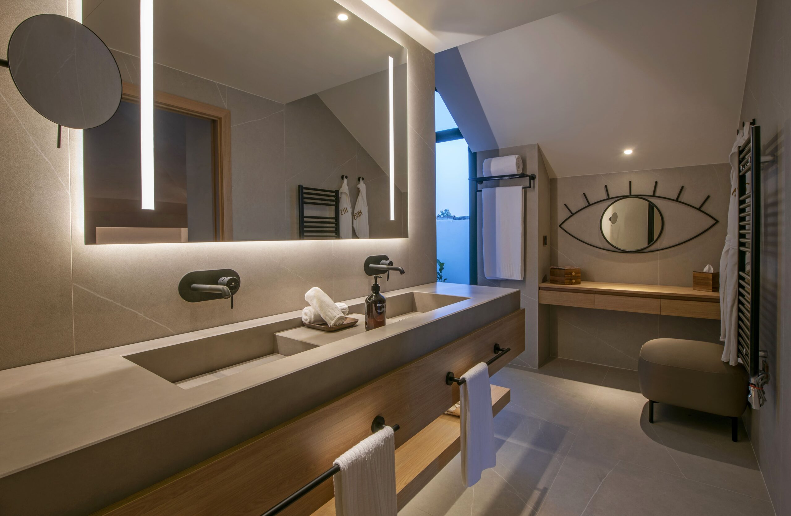 A luxury bathroom with a double sink and a lit mirror above it, complete with modern furnishings.