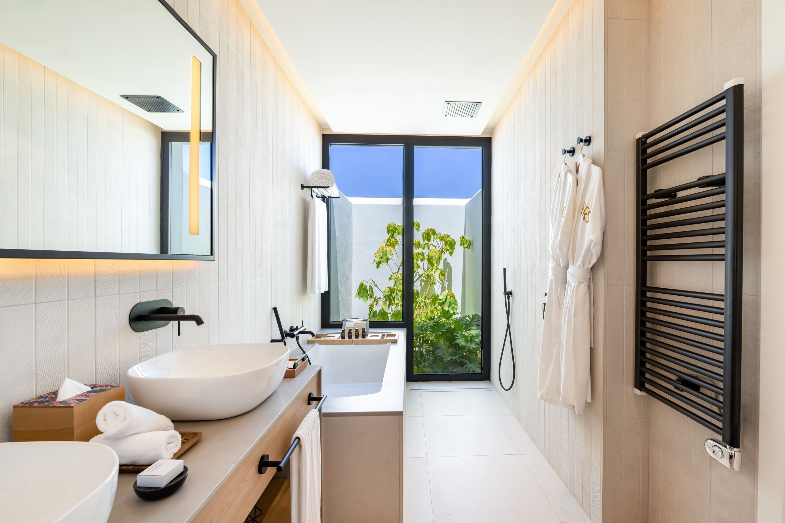 A bathroom in the luxury hotel with a relaxing bathtub, double sink and complimentary bathrobes.