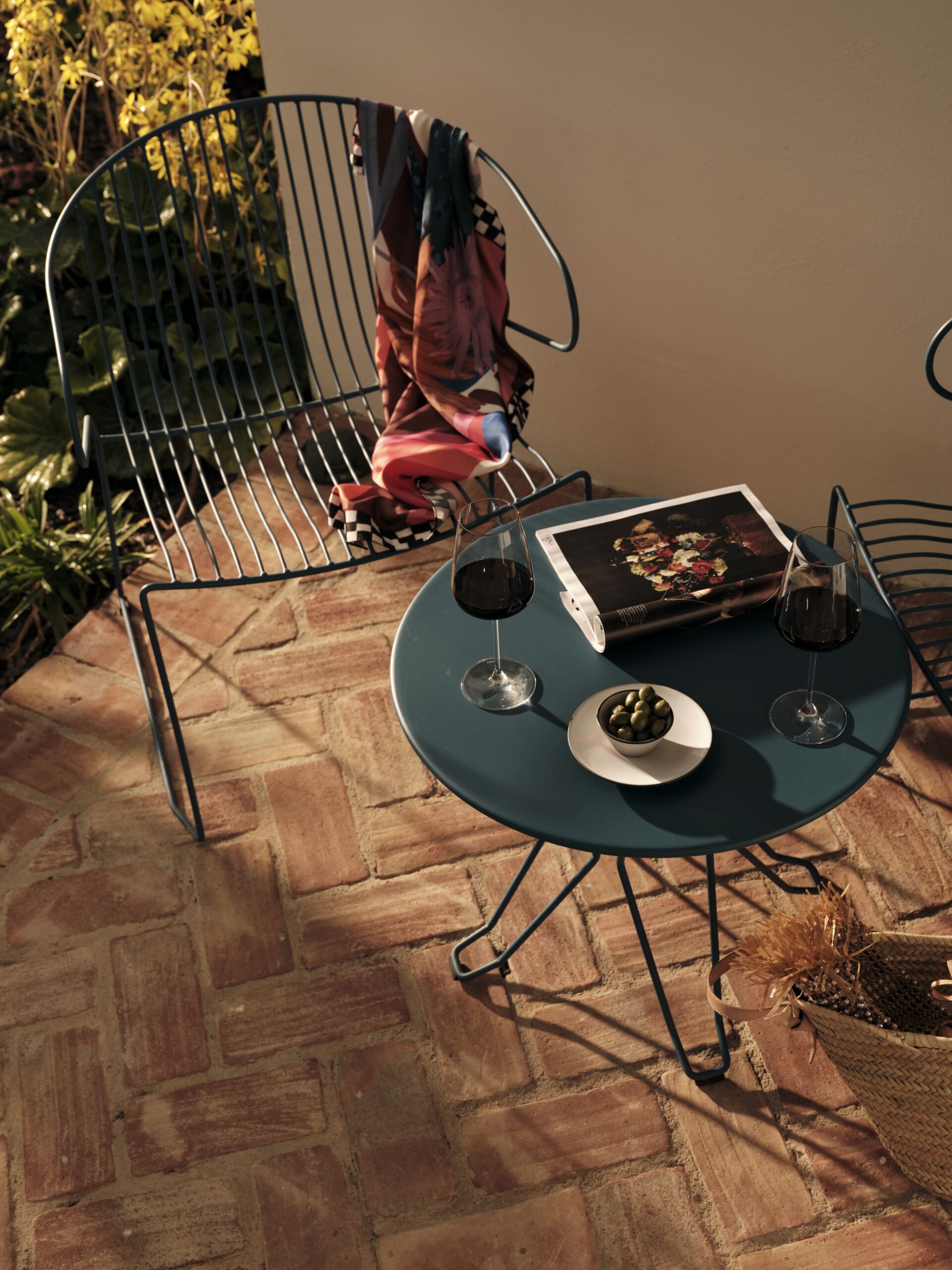 Two chairs and a table with wine, olives and a magazine.