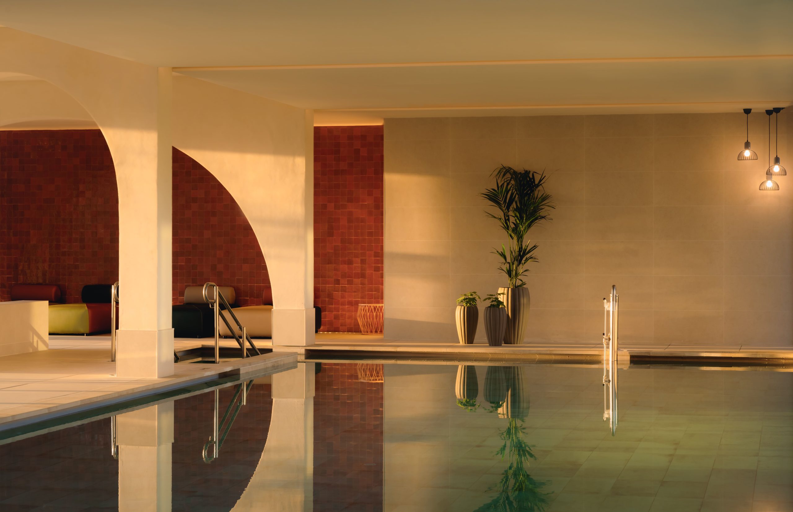 A spacious indoor pool at the luxury hotel with potted plants at the edge of the pool.