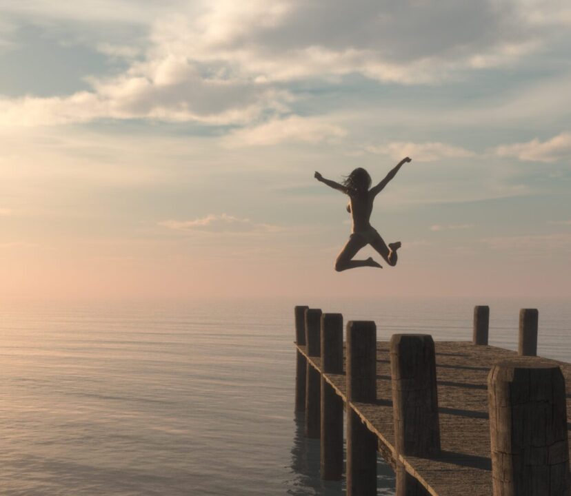 Solo female traveller jumps off a pontoon into the ocean.