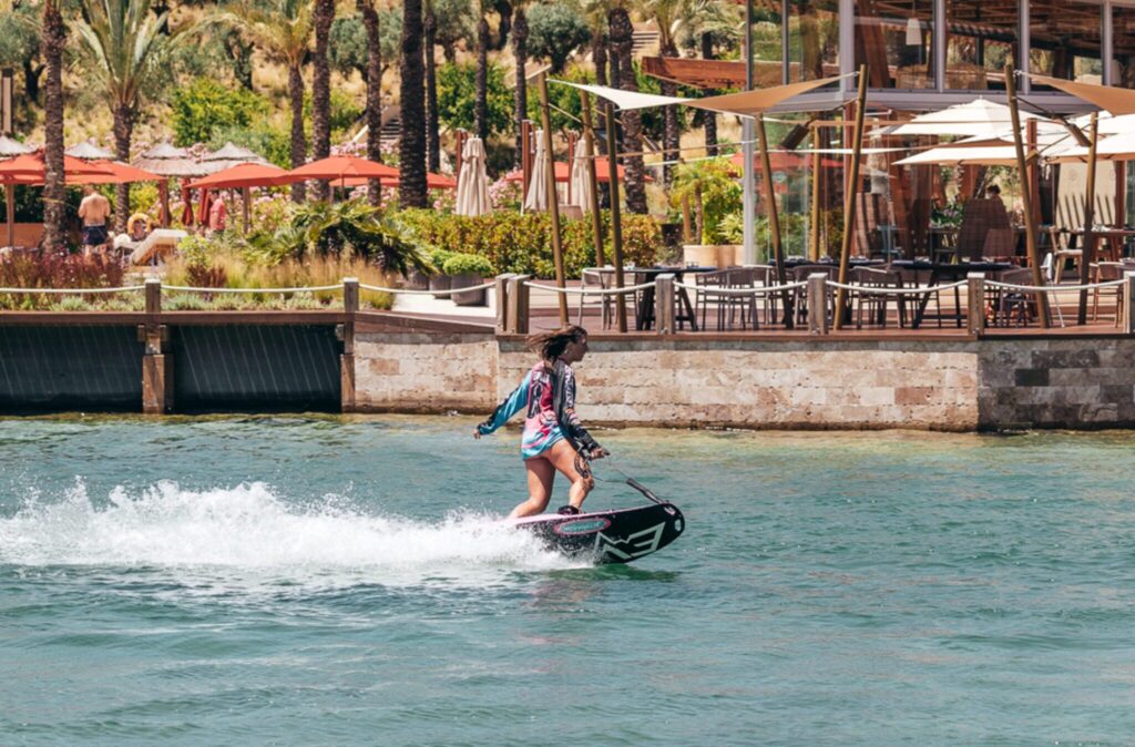 The Beach at La Reserva showing a woman on a hydrofoil on the lagoon with the restaurant behind.