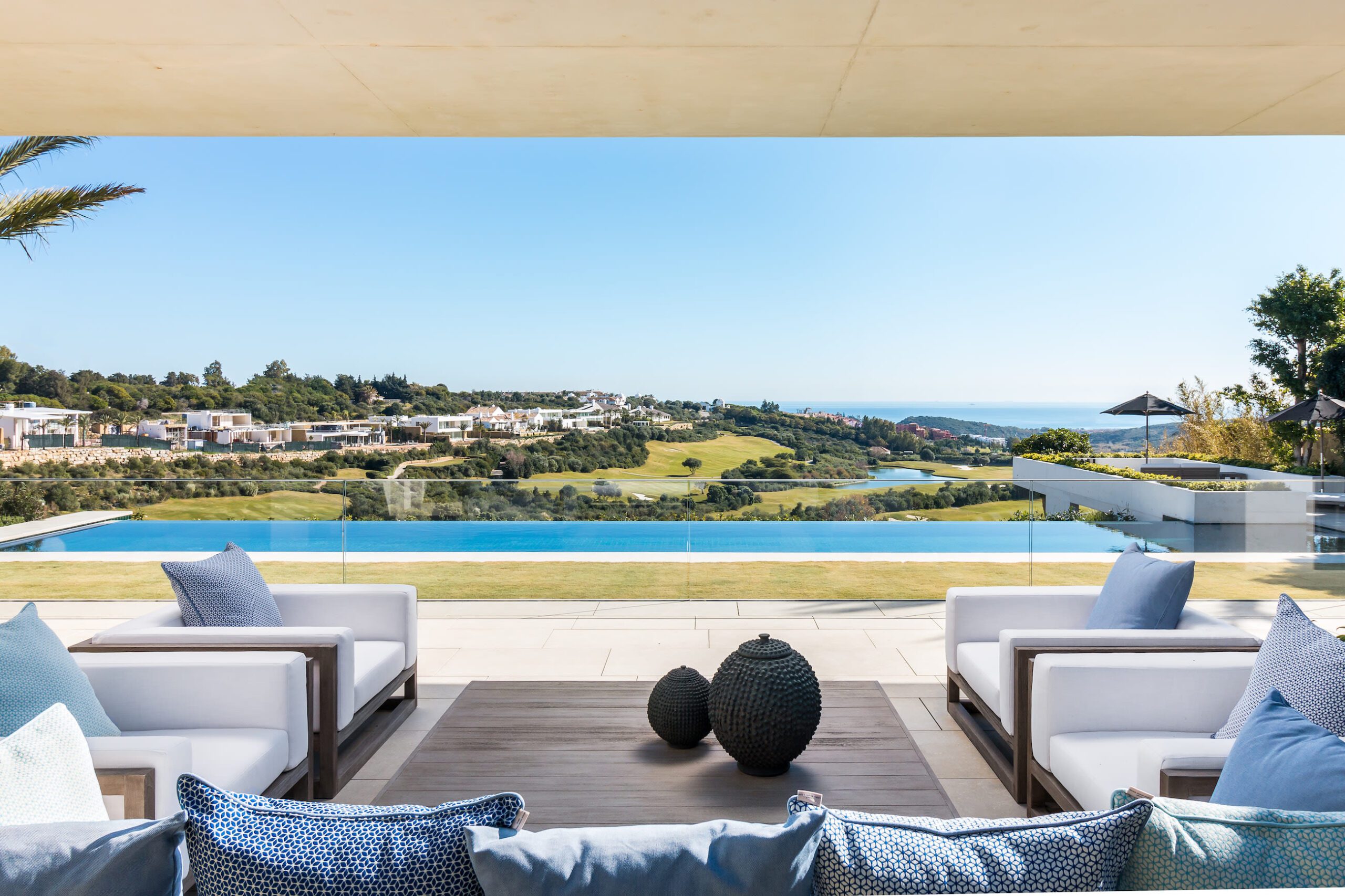 An outdoor seating area with a view of the infinity pool and views of the ocean.