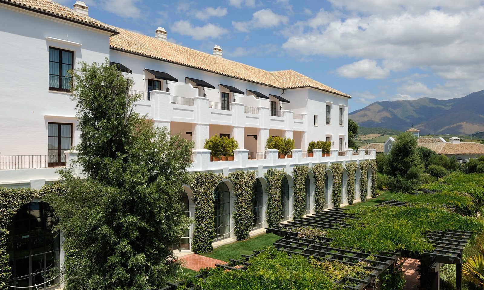 A view of the outside of the hotel surrounded by greenery with views of the mountains in the distance.