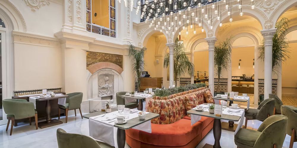 An indoor dining area at the luxury hotel with perfectly set tables, comfortable seating and potted plants.