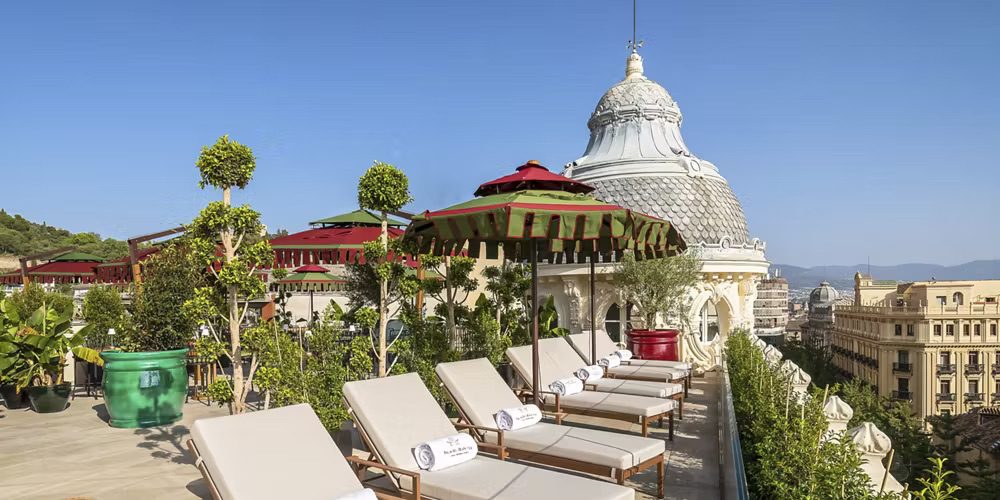 The terrace at the luxury hotel, featuring an array of sun loungers and umbrellas, perfect to relax after a day of solo travel, complete with incredible views over Granada.