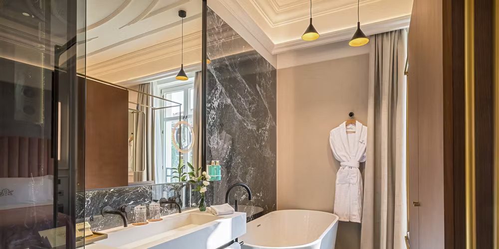 A bathroom at the luxury hotel with a sink, bathtub, shower and a complimentary bathrobe.