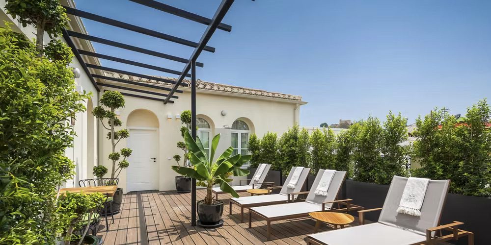 A balcony at the luxury hotel, featuring four sun loungers surrounded by lush greenery.