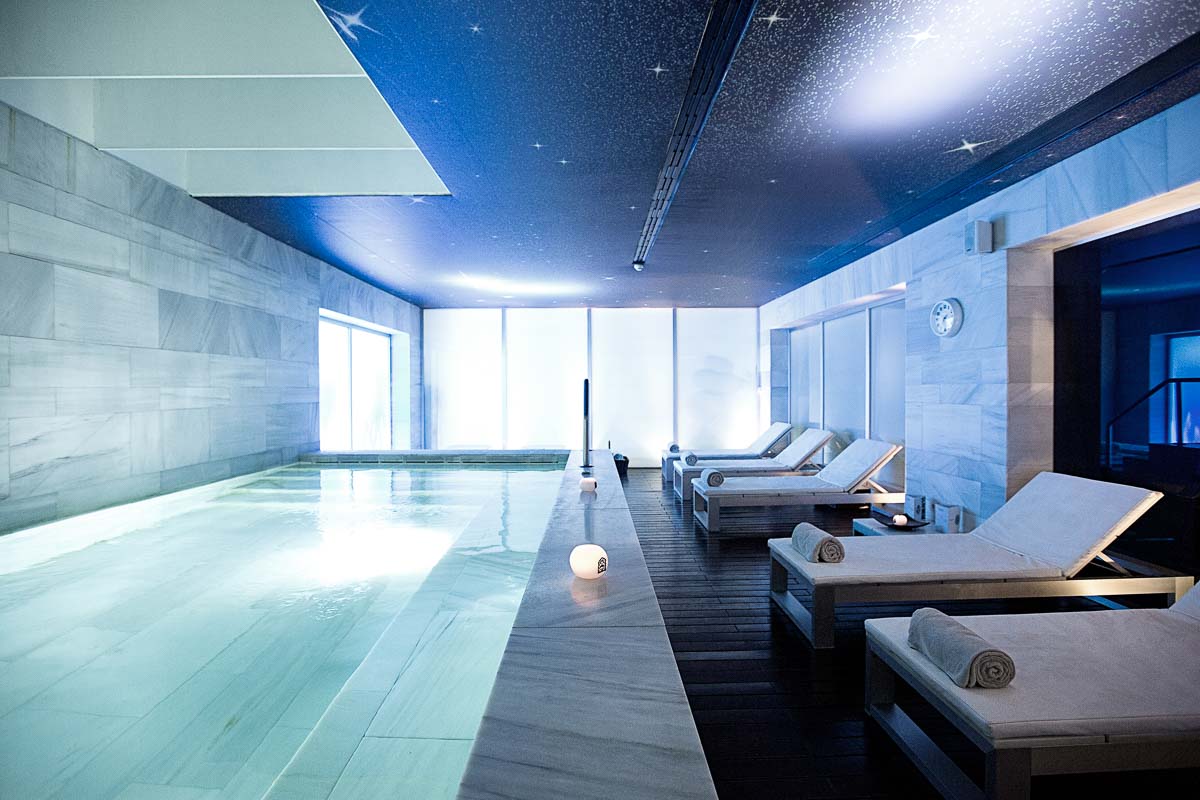 An indoor pool with loungers lining the edge of the pool.