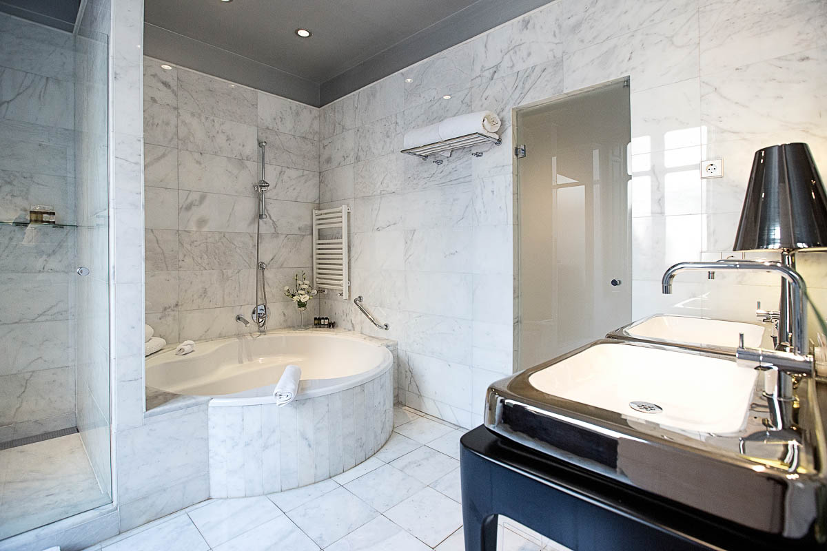 A bathroom at the luxury hotel, showcasing a shower, bathtub and a double sink.