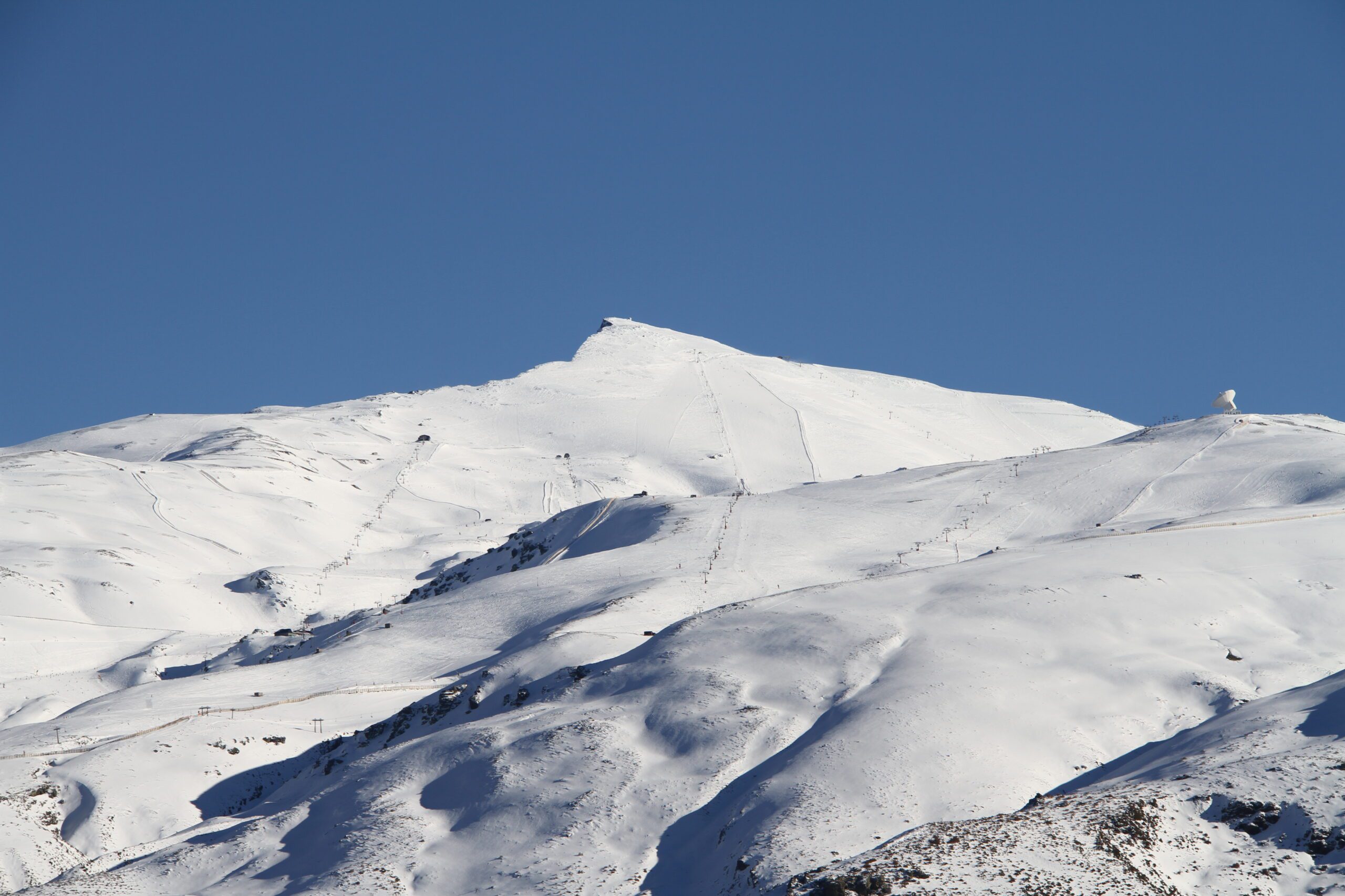 Valeta Peak in Sierra Nevada in Granada Spain covered in deep white snow with a deep bluw sky behind