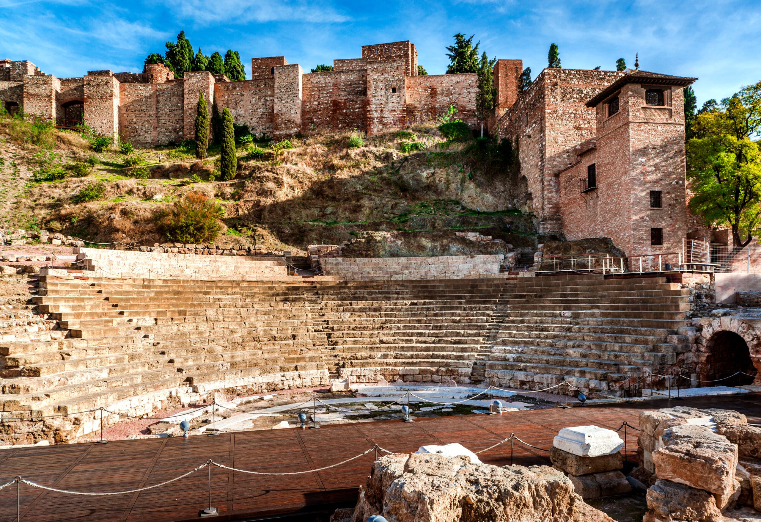 A view of the Roman Theatre at the bottom of the Alcazaba fortress, showing the semi-circular seating carved out of stone.