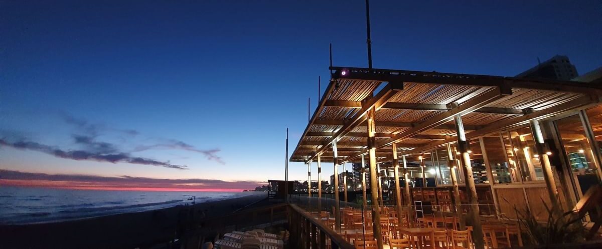 A view of the restaurant at the hotel with the beach and sunset in the background.