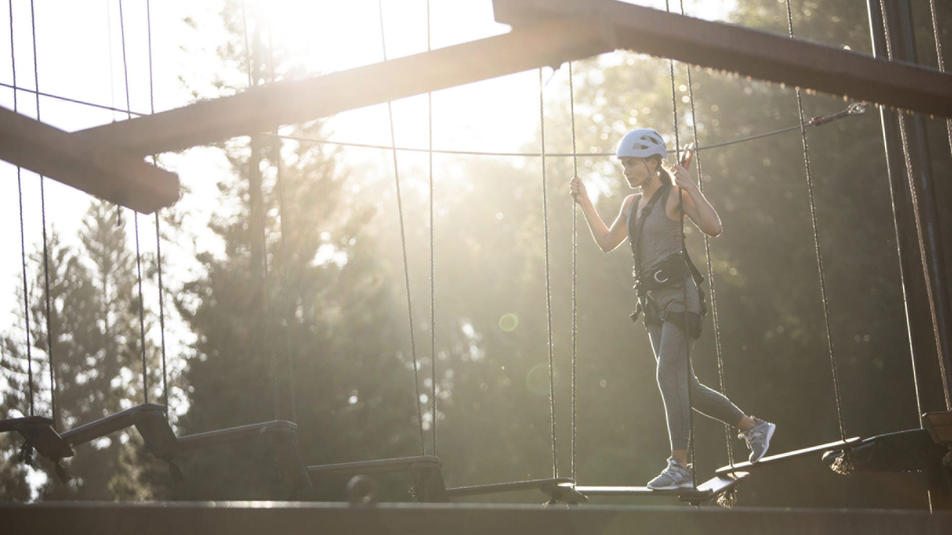 An elegant lady confidently traversing a rope bridge, exuding sophistication and grace on an adventure.