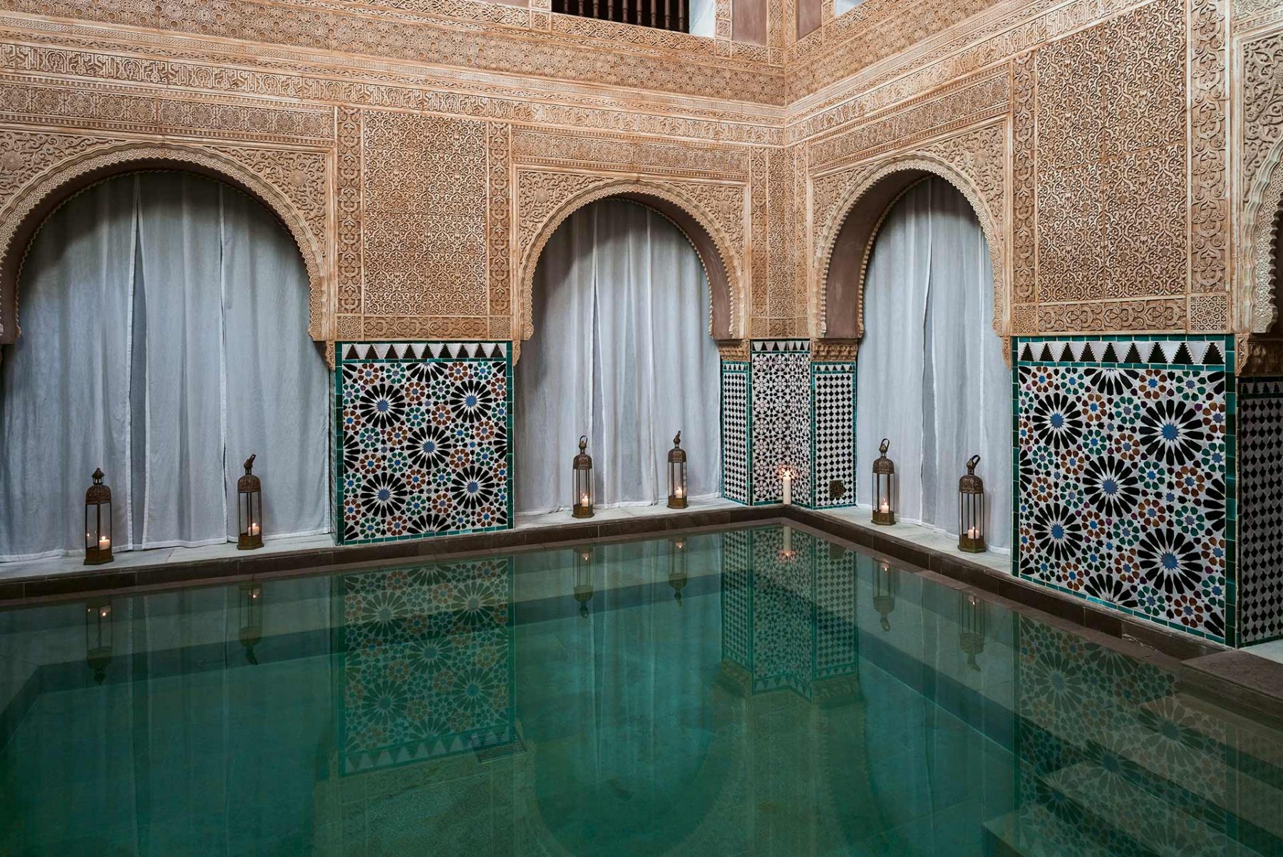 An Arab bath in the luxury spa with candles lit around the edge of the water and beautiful tiles lining the walls, complete with natural light flooding from the ceiling.