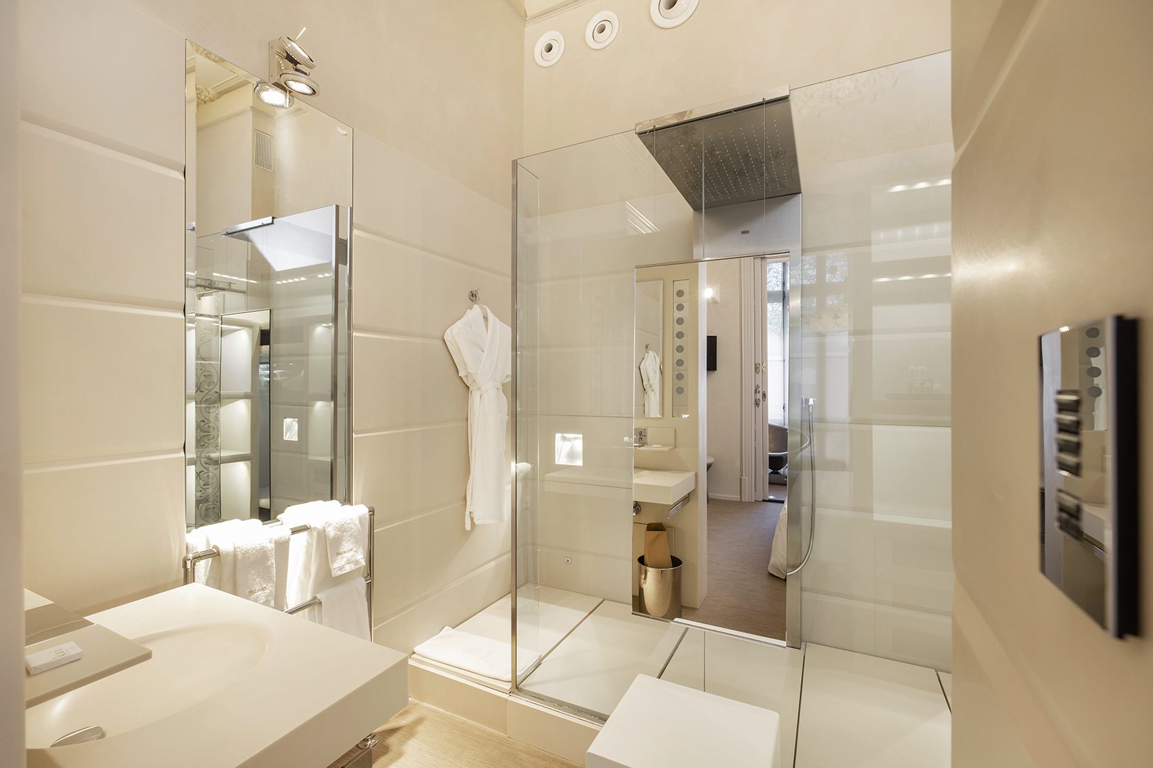 A luxury bathroom with a rainfall shower, sink and full length mirror.