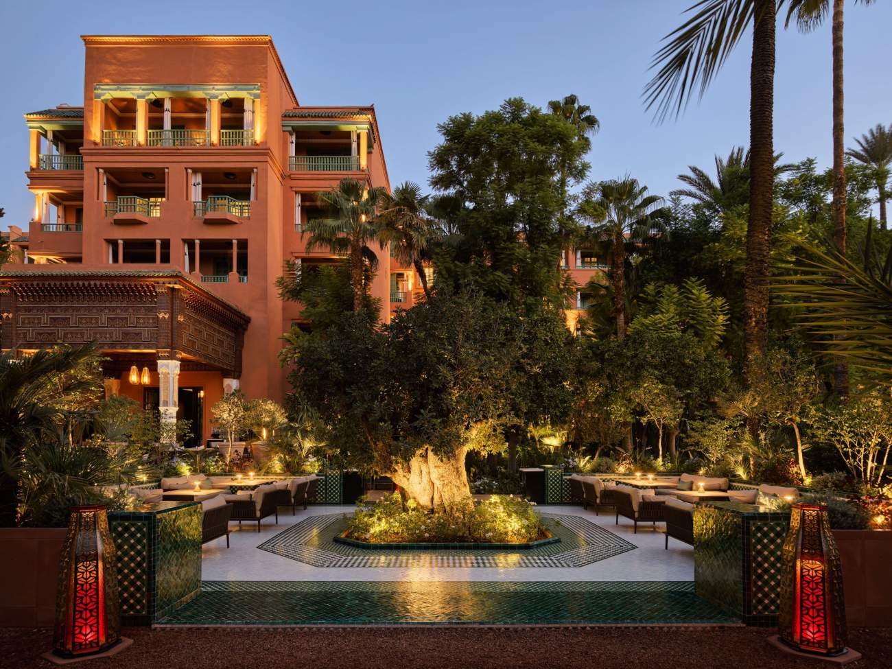 An outdoor dining area, surrounded by palm trees and greenery with an incredible tree feature in the centre of the space.