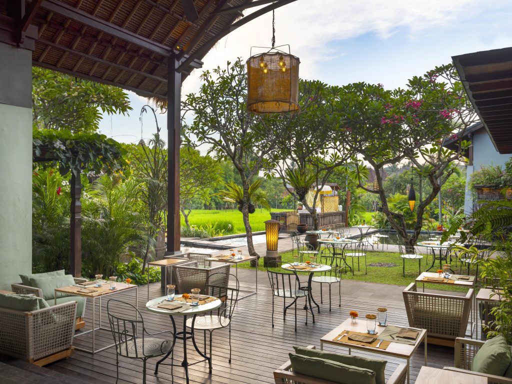 An outdoor dining area, surrounded by lush greenery and relaxing water features, perfect for a solo female traveller to enjoy the Alaya Resort's luxury dining facilities.