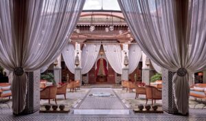 Luxury dining area with traditional Moroccan tile work on the floor and pillars, complete with intricate curtains, surrounding the area.