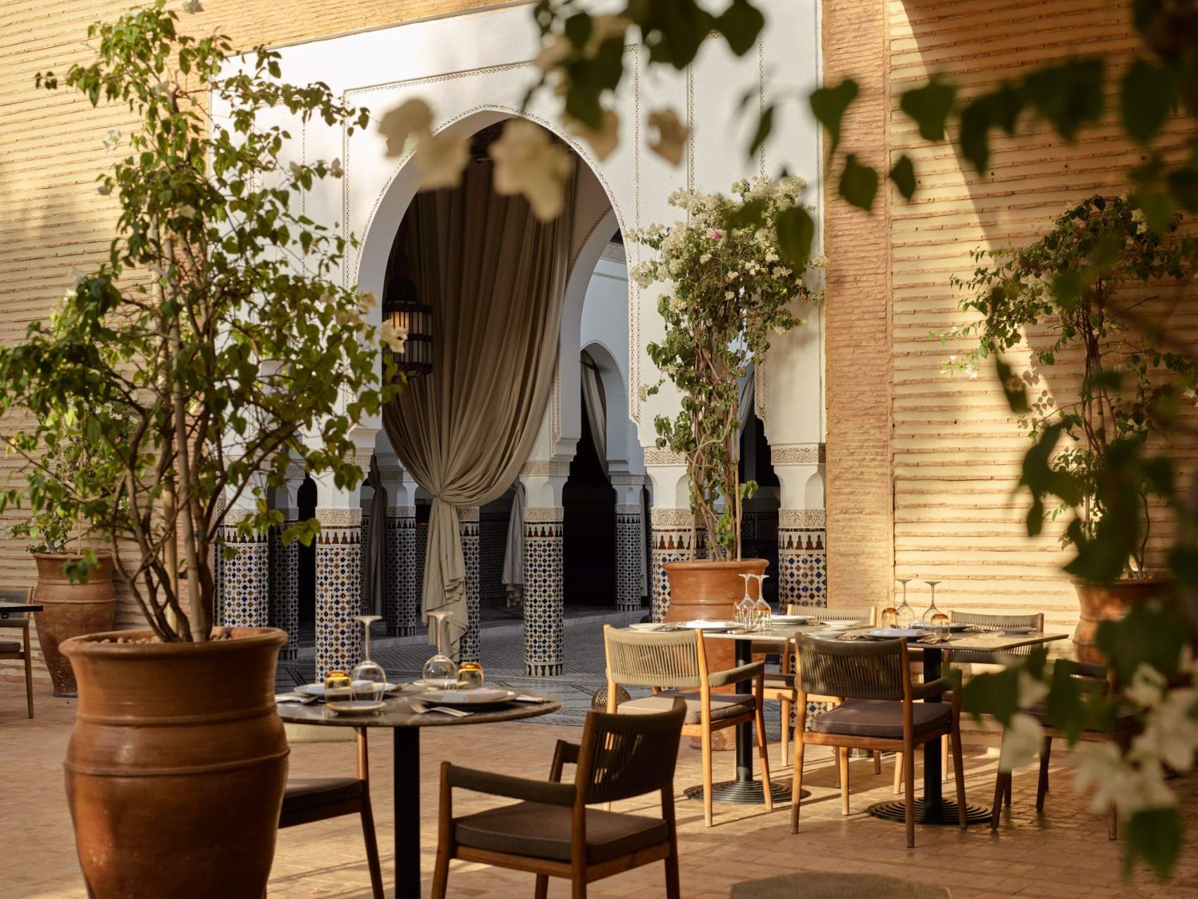 Luxury outdoor seating area with elegant tables and chairs and gorgeous potted plants outside the grand La Mamounia Hotel.