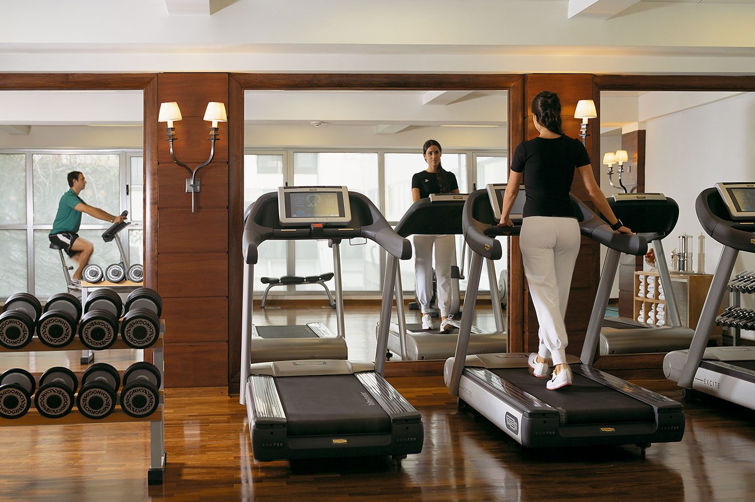 A woman using a treadmill in a well-equipped gym featuring a variety of machines and equipment.