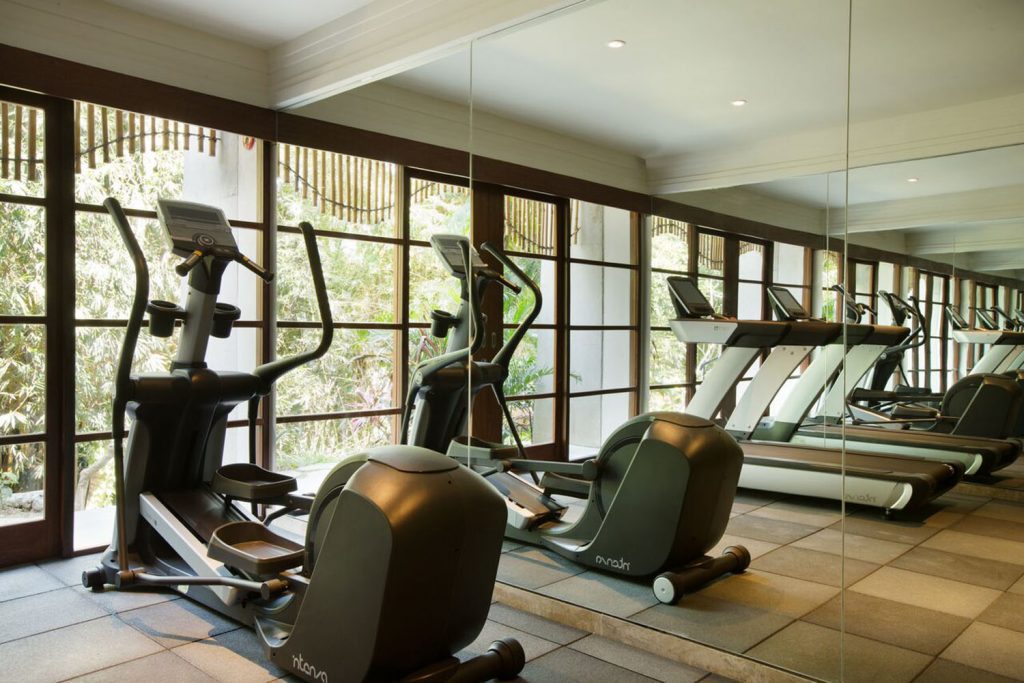 A luxury gym featuring premium exercise equipment with sleek mirrors and large windows showcasing the incredible view.