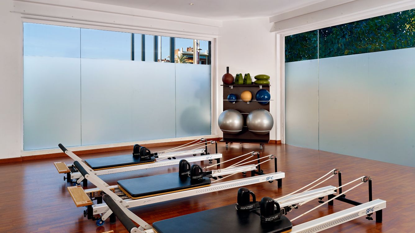 Three pilates machines and equipment in a room, with frosted glass windows, ensuring privacy for the solo female traveller.