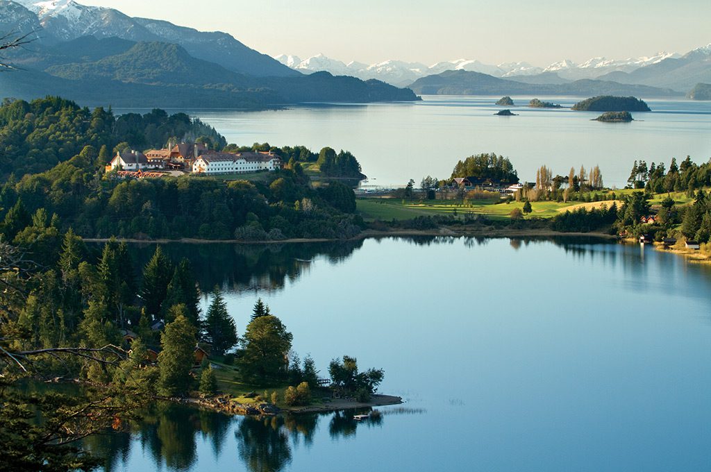 A view of the luxury hotel surrounded by serene lakes, greenery and incredible mountains behind.