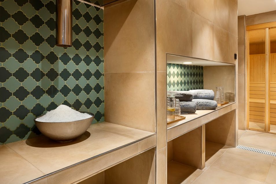 A room in the luxury spa with neatly folded towels, jugs of water and lemon and a doorway to the sauna.