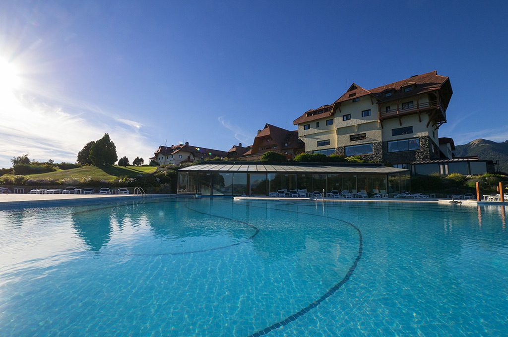 A vast outdoor pool with views of the luxury hotel and incredible mountains behind.