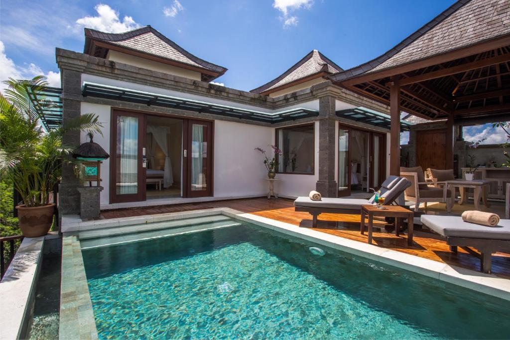 A view of the luxury accommodations at the resort from the outside, showing the outdoor pool, comfortable sun loungers and outdoor furniture.