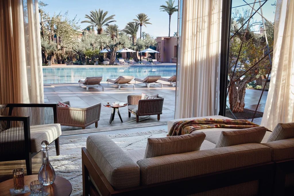 A sheltered outdoor living area with sofas and chairs, positioned to offer a view of the outdoor pool and scenic landscape, complete with curtains for a moment of privacy.