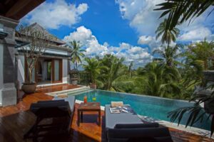 A view from outside a bedroom at the resort, showcasing the private terrace with a luxury outdoor pool, sun loungers and an incredible view of the Indonesian scenery.