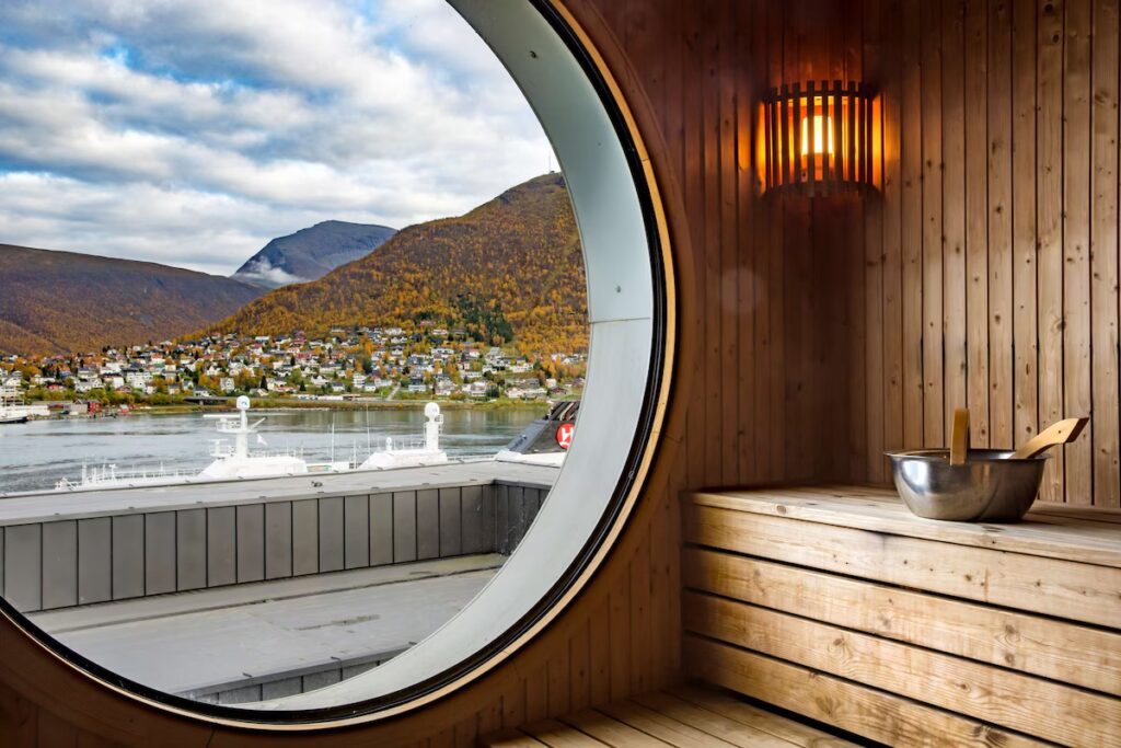 A wooden sauna with a large circular window looking onto the incredible Tromsø.