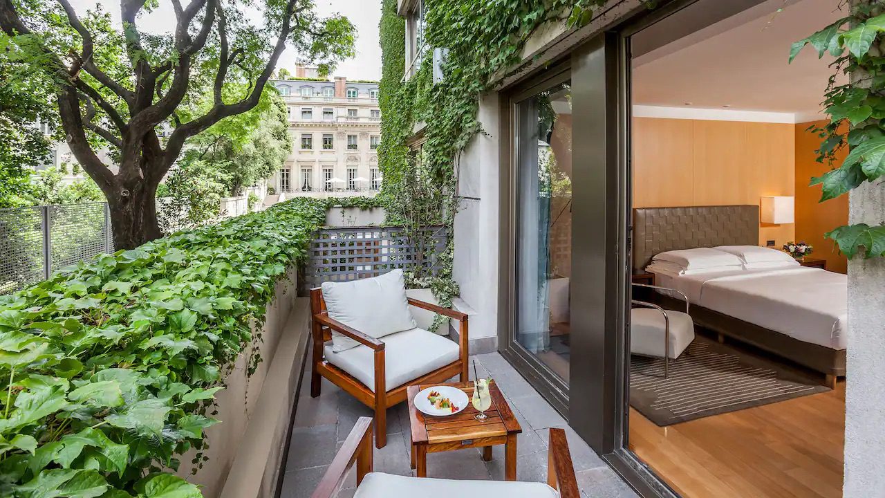 A private balcony outside one of the luxury hotel's rooms. The balcony is complete with two outdoor chairs, a table and ivy covering the walls.