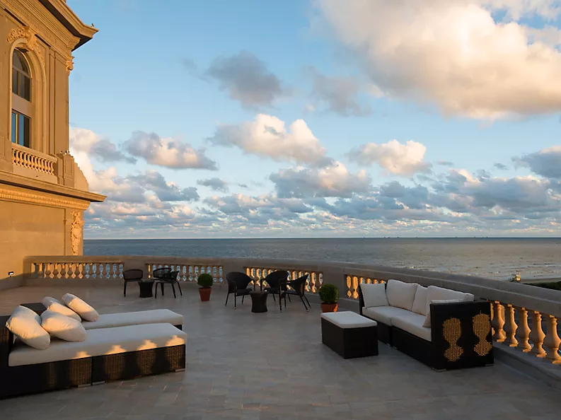 The terrace of the luxury hotel with a variety of outdoor seating with a view overlooking the ocean.