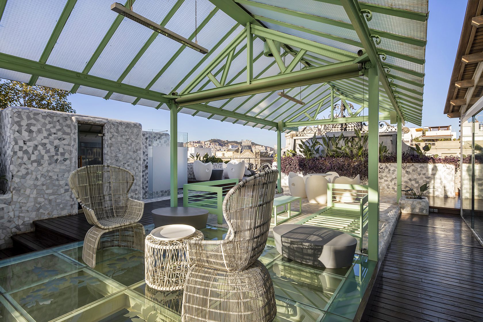 The terrace at the luxury hotel with an array of seating and tables, a sauna and views over Barcelona.