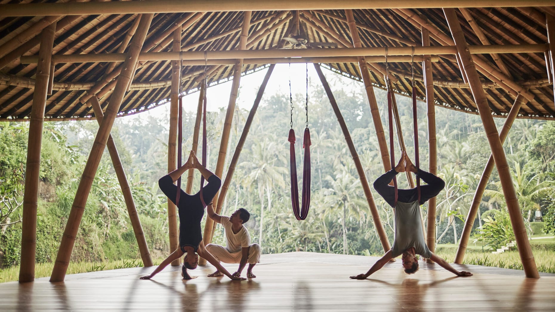 Two people being guided through anti-gravity yoga at the hotel's Sacred River Spa, complete with incredible views of the lush greenery in the background.