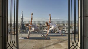 Two women enjoying yoga on a terrace at the luxury hotel, overlooking the incredible Madrid skyline.