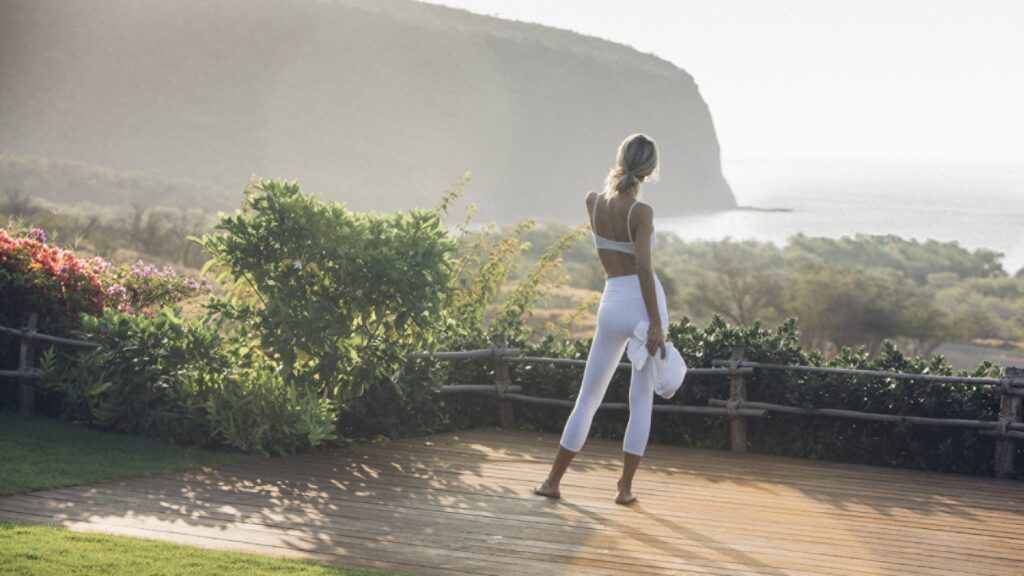 A woman about to start a morning yoga session overlooking Hulopoe bay.