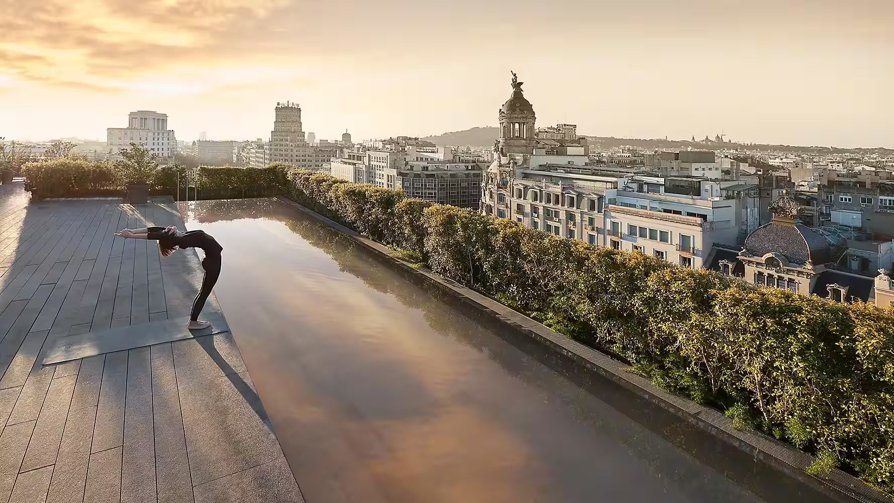 A woman enjoying morning yoga at Mandarin Oriental with incredible views over Barcelona's skyline.