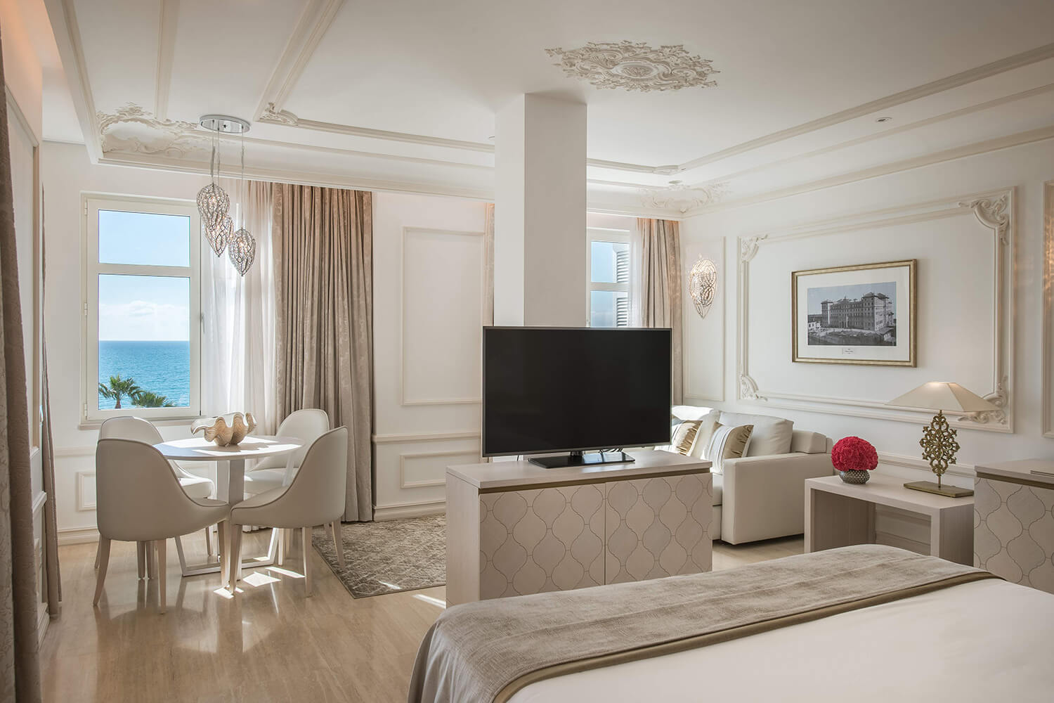 A bedroom at the luxury hotel featuring a TV, a table and chairs, a sofa, complete with views of the coast.