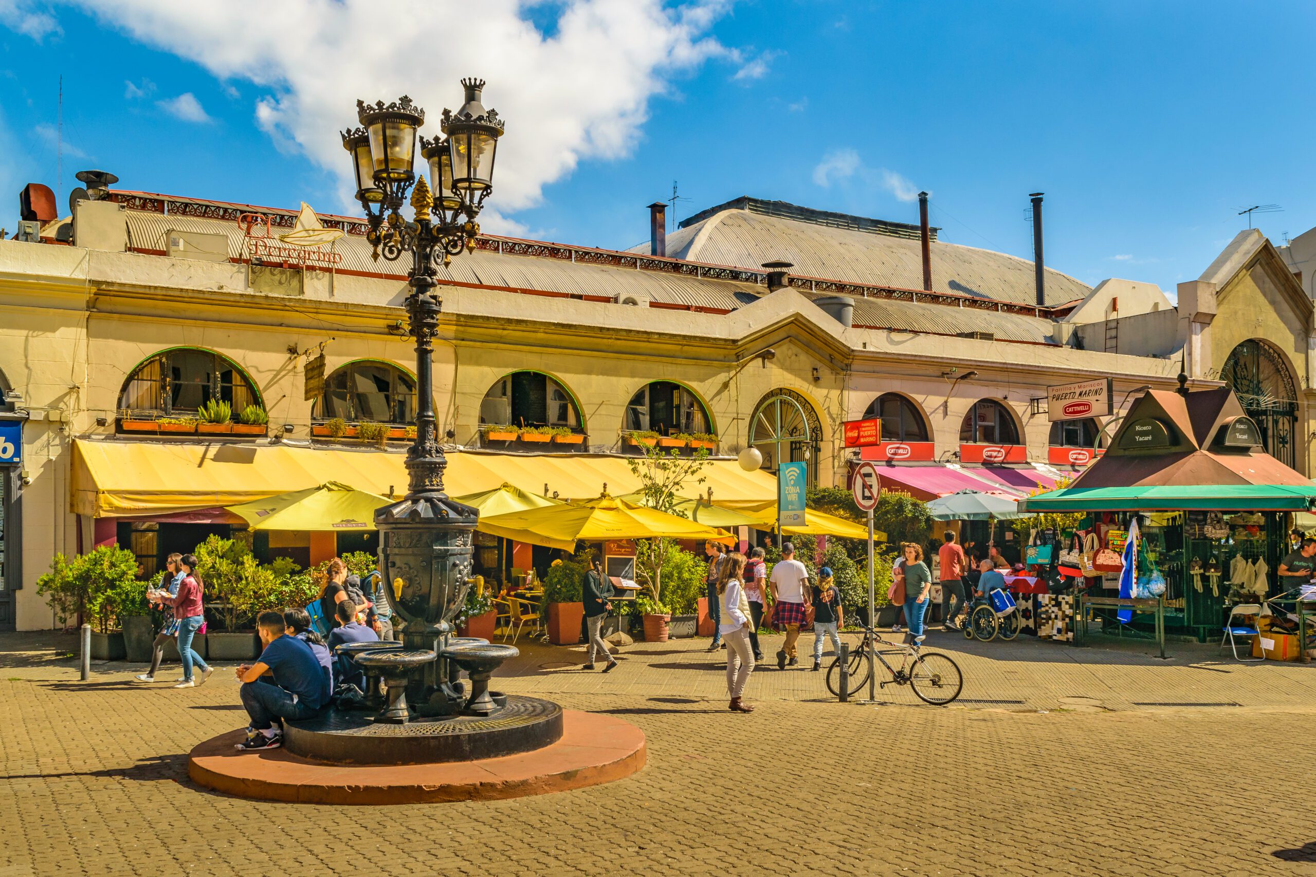 A view of a traditional food market in Montevideo's old town with an old lamppost in the centre and a blue sky in the background.