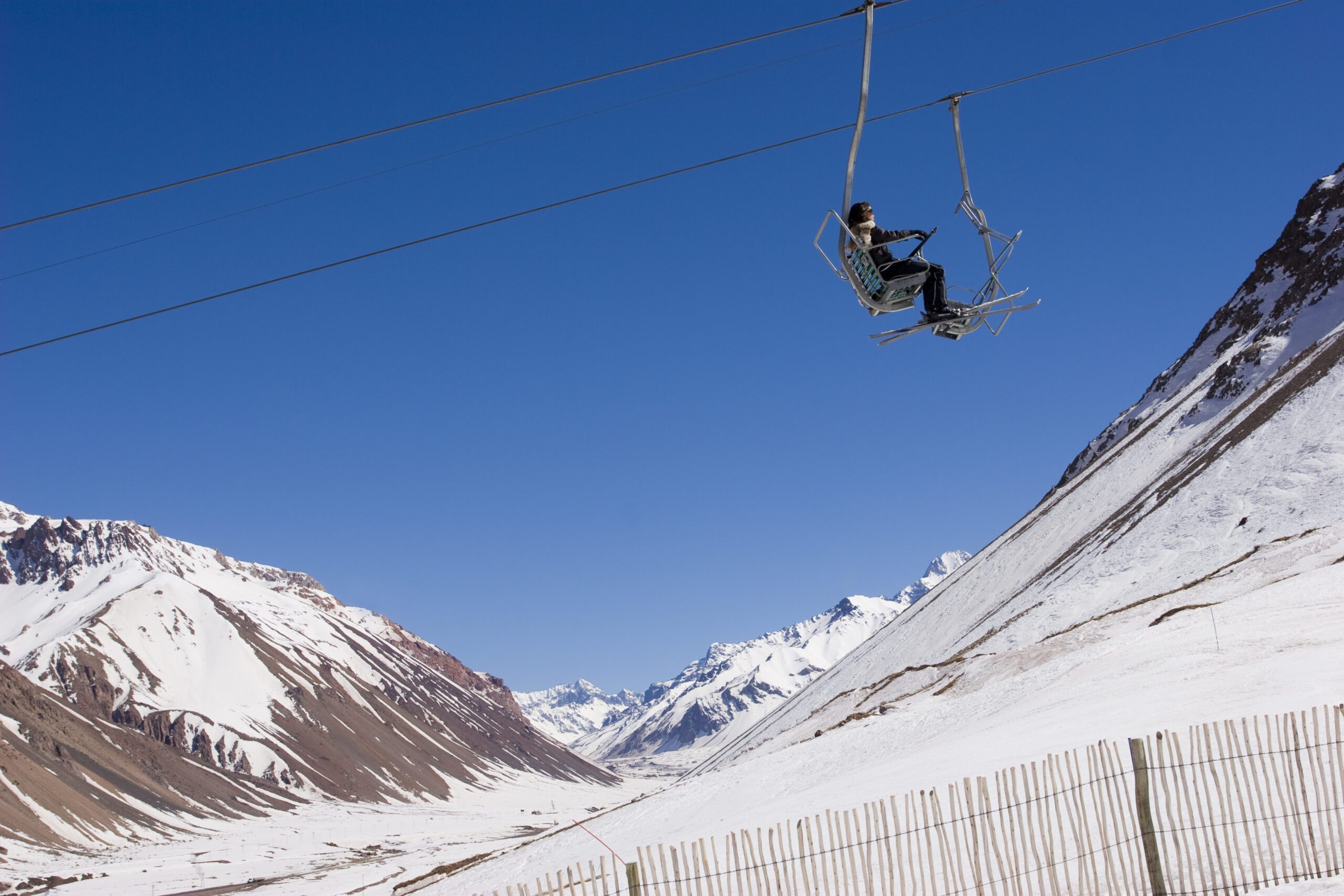 Solo Skiier on a ski lift above the snow with a clear deep blue sky backdrop in Penitentes Mendoza Argentina