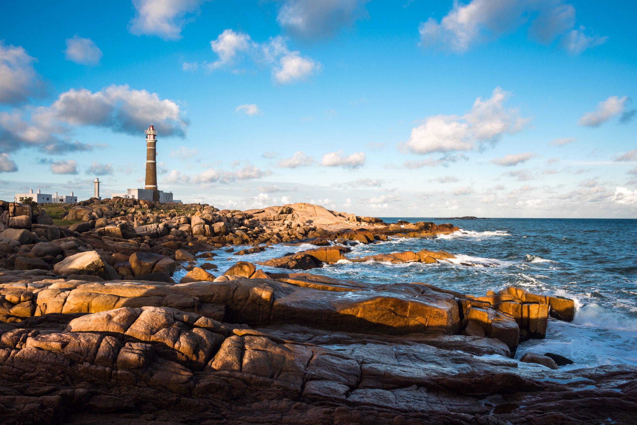 Lighthouse in Cabo Polonio Rocha Uruguy in the distance with rocks and a calm shoreline in front