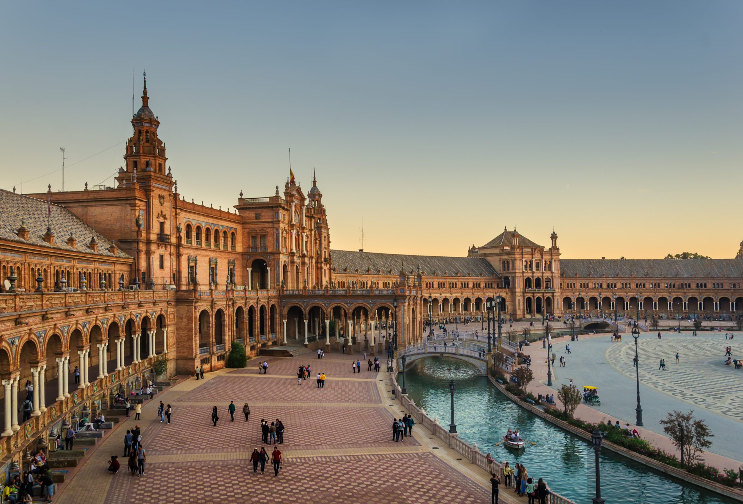 The old buildings of Plaza Mayor in Seville, Spain with the walkway along the river in front. Picture taken at Sunset.