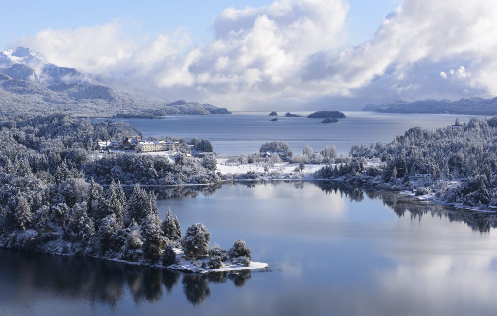 Lakes in Bariloche Argentina in winter showing snow on the ground and snowcapped mountains behind