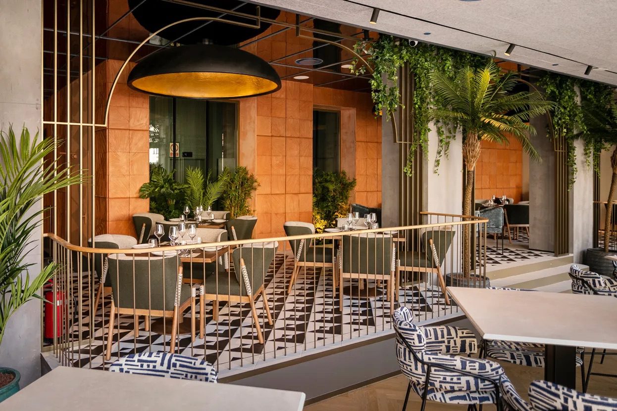 A dining area at the luxury hotel with an array of tables, chairs and plants.